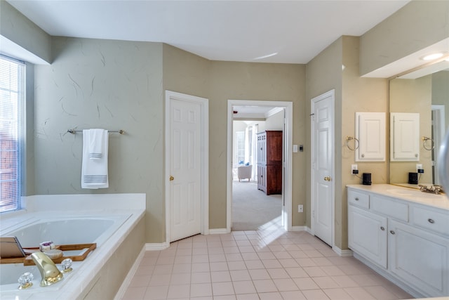 bathroom featuring tile patterned flooring, vanity, and a relaxing tiled tub