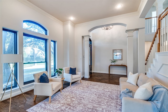 living room featuring a chandelier, hardwood / wood-style floors, ornate columns, and ornamental molding