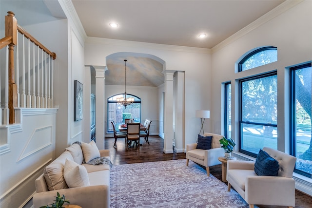 living room featuring wood-type flooring, decorative columns, ornamental molding, and a notable chandelier