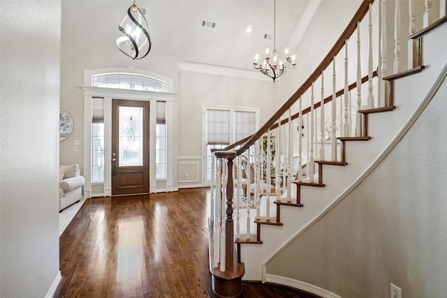 entryway with crown molding, dark wood-type flooring, a chandelier, and a high ceiling