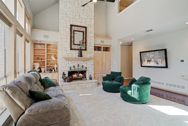 carpeted living room featuring a stone fireplace, high vaulted ceiling, and built in shelves