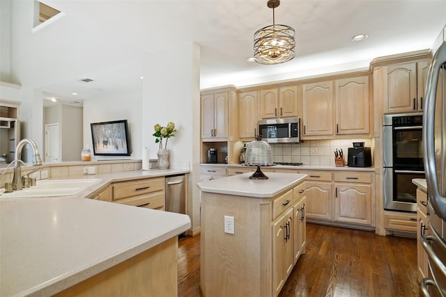 kitchen featuring stainless steel appliances, light brown cabinetry, a center island, and sink