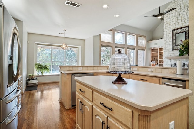 kitchen with appliances with stainless steel finishes, dark hardwood / wood-style floors, pendant lighting, a center island, and kitchen peninsula