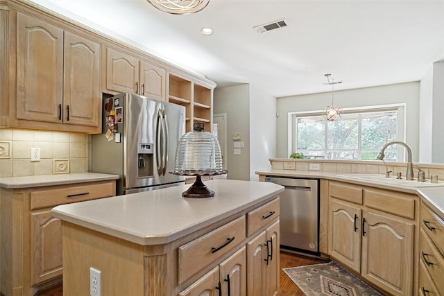 kitchen featuring sink, a center island, hanging light fixtures, stainless steel appliances, and backsplash