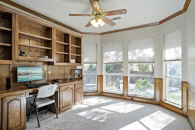 carpeted office with crown molding, built in desk, and a wealth of natural light