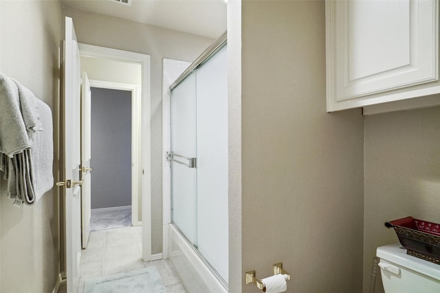 bathroom featuring bath / shower combo with glass door and toilet