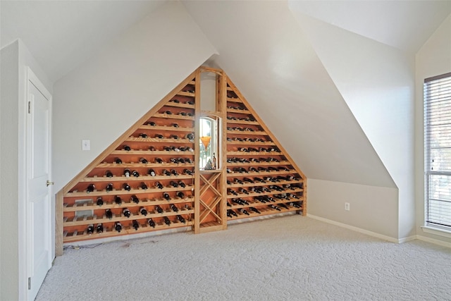 wine area featuring vaulted ceiling and carpet flooring