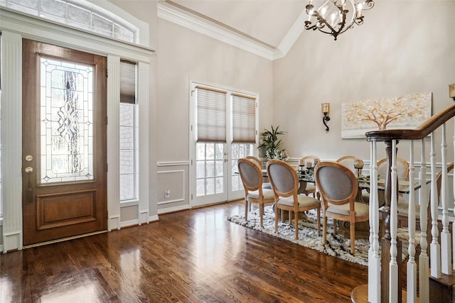 entrance foyer with dark hardwood / wood-style flooring, high vaulted ceiling, ornamental molding, and a chandelier