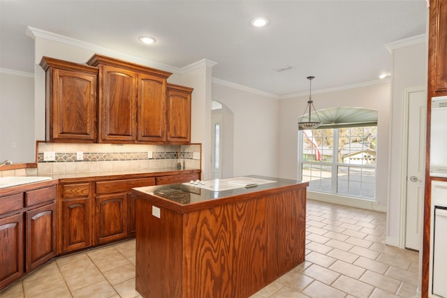 kitchen with backsplash, sink, hanging light fixtures, ornamental molding, and a kitchen island