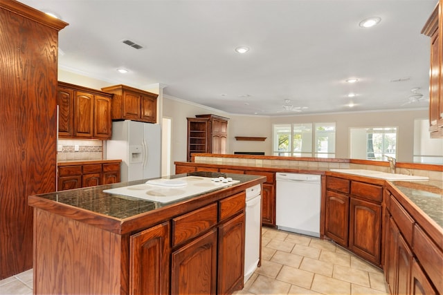 kitchen with white appliances, crown molding, sink, ceiling fan, and a kitchen island