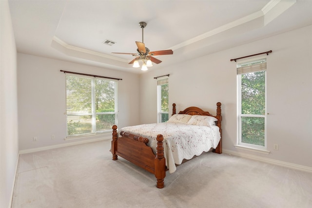 carpeted bedroom with a raised ceiling, ceiling fan, and ornamental molding