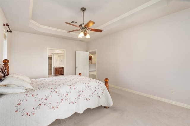 bedroom with a raised ceiling, carpet floors, ensuite bath, and ceiling fan