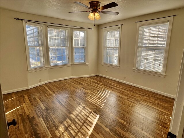 empty room with a wealth of natural light, ceiling fan, a textured ceiling, and hardwood / wood-style flooring