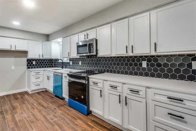 kitchen featuring white cabinets, appliances with stainless steel finishes, backsplash, and dark wood-type flooring