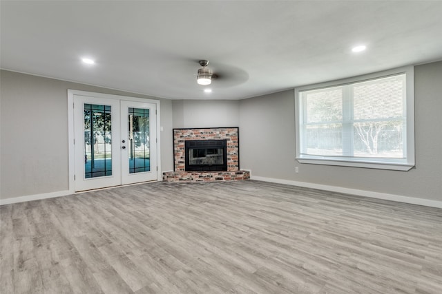 unfurnished living room featuring a healthy amount of sunlight, light hardwood / wood-style floors, and french doors