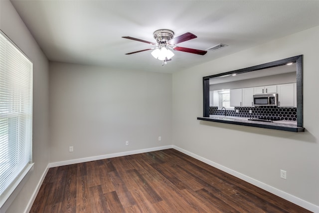 empty room featuring ceiling fan, sink, and dark wood-type flooring