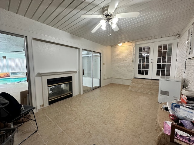 interior space featuring a tile fireplace, ceiling fan, and french doors