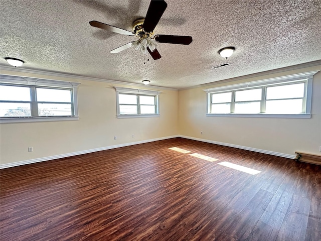 empty room with dark wood-type flooring, ornamental molding, and a textured ceiling