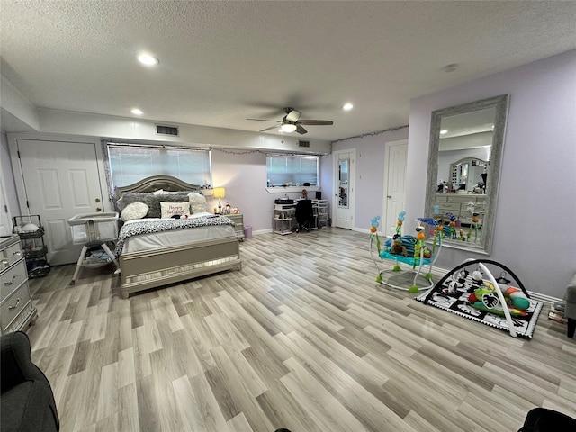 bedroom with ceiling fan, light hardwood / wood-style floors, and a textured ceiling