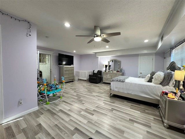 bedroom featuring ceiling fan, light hardwood / wood-style floors, and a textured ceiling