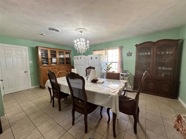 dining area featuring light tile patterned floors, a textured ceiling, and a notable chandelier