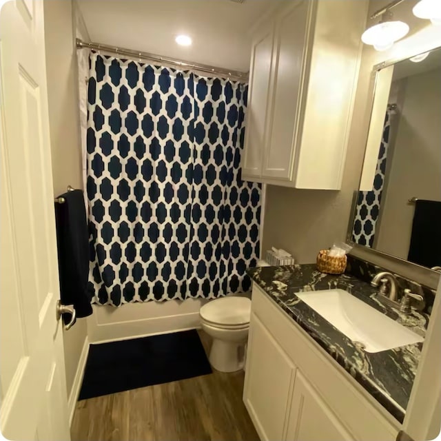 full bathroom featuring hardwood / wood-style flooring, vanity, shower / bath combo, and toilet