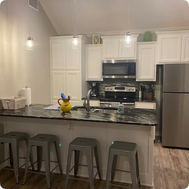 kitchen featuring white cabinetry, tasteful backsplash, appliances with stainless steel finishes, dark stone counters, and light hardwood / wood-style floors