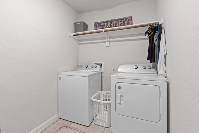 clothes washing area with washer and dryer and light tile patterned floors