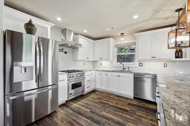 kitchen featuring sink, stainless steel appliances, white cabinets, decorative light fixtures, and wall chimney exhaust hood