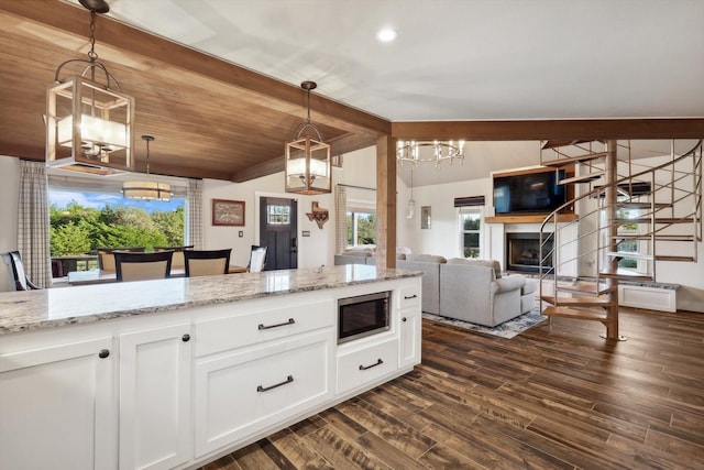 kitchen with built in microwave, white cabinetry, vaulted ceiling with beams, and pendant lighting