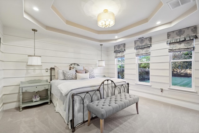 carpeted bedroom featuring a raised ceiling and a notable chandelier