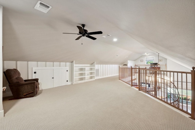 additional living space with vaulted ceiling, light carpet, built in features, and ceiling fan