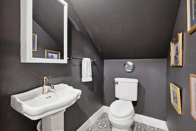 bathroom with lofted ceiling, toilet, sink, and a textured ceiling