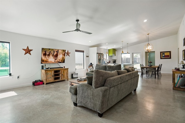 living room with ceiling fan with notable chandelier, concrete flooring, and a wealth of natural light