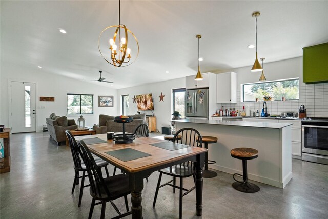 dining space with vaulted ceiling, concrete flooring, and ceiling fan with notable chandelier