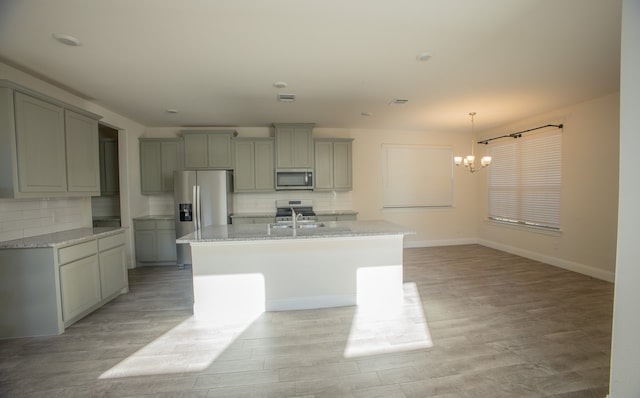 kitchen with light wood-type flooring, stainless steel appliances, and an island with sink