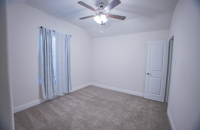 empty room with ceiling fan, vaulted ceiling, and light carpet