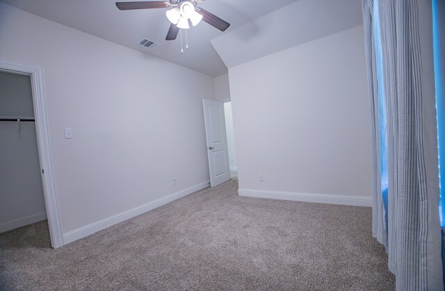 unfurnished bedroom featuring a walk in closet, ceiling fan, a closet, and light colored carpet