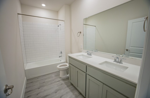 full bathroom with tiled shower / bath combo, wood-type flooring, vanity, and toilet