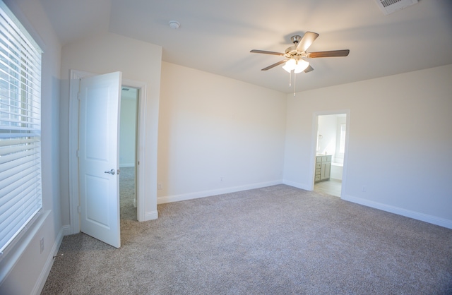 unfurnished bedroom with ensuite bathroom, light colored carpet, and ceiling fan