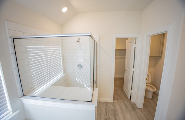 bathroom with wood-type flooring, vaulted ceiling, a shower with door, and toilet