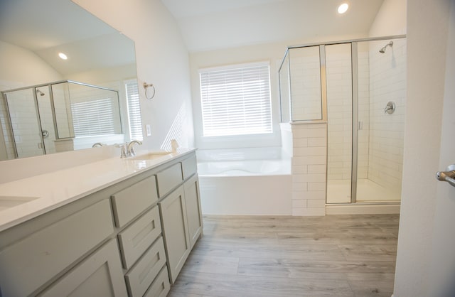 bathroom with hardwood / wood-style flooring, vaulted ceiling, separate shower and tub, and vanity