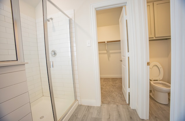 bathroom featuring hardwood / wood-style flooring, a shower with door, and toilet