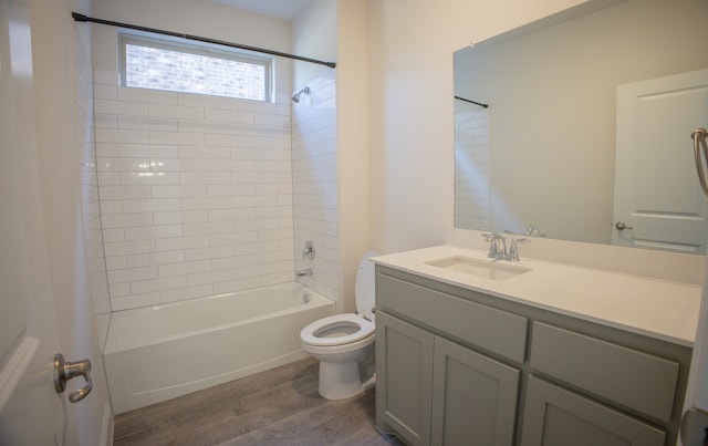 full bathroom with hardwood / wood-style floors, tiled shower / bath combo, toilet, and vanity