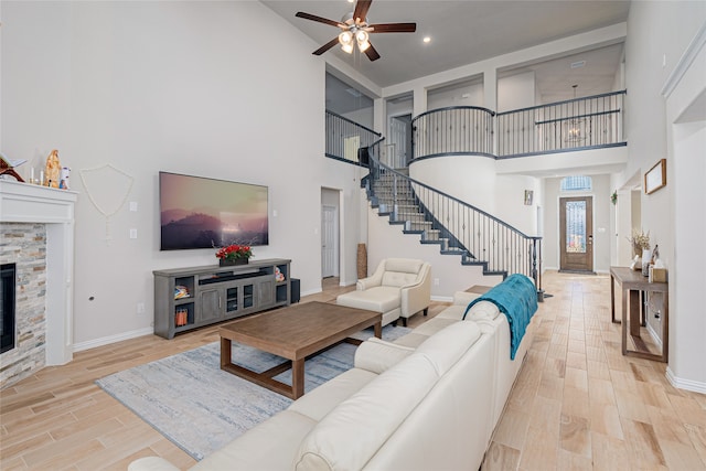 living room featuring a fireplace, a towering ceiling, and light hardwood / wood-style flooring