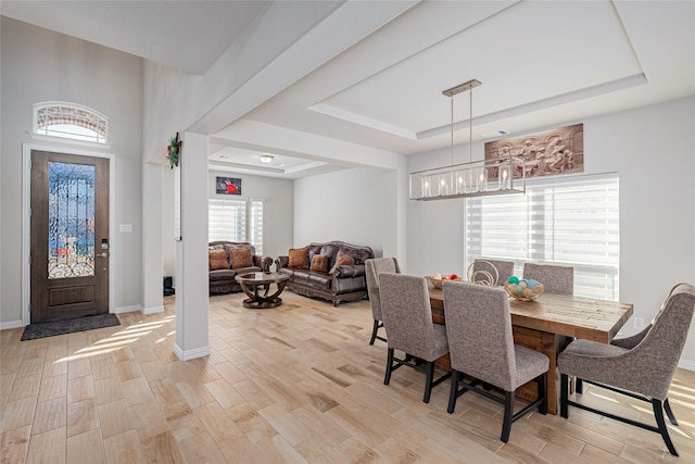 dining area with light wood-type flooring and a tray ceiling