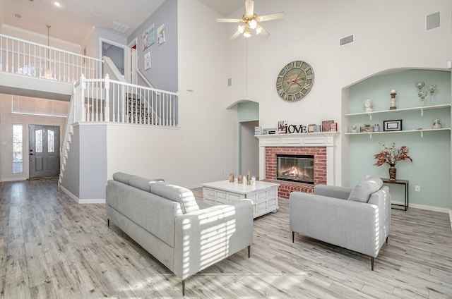 living room featuring ceiling fan, light hardwood / wood-style floors, a fireplace, and high vaulted ceiling