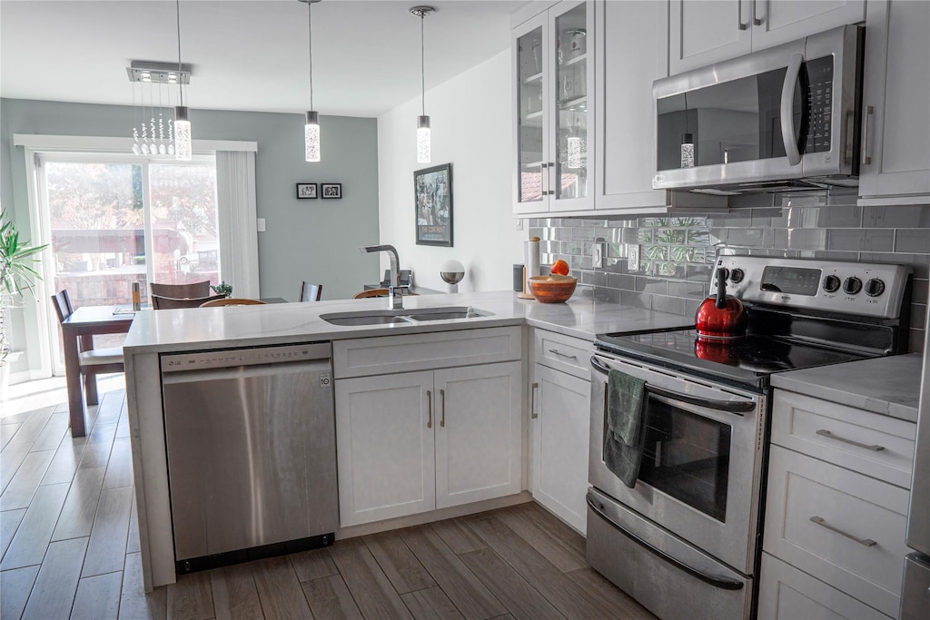 kitchen with appliances with stainless steel finishes, sink, white cabinets, and kitchen peninsula