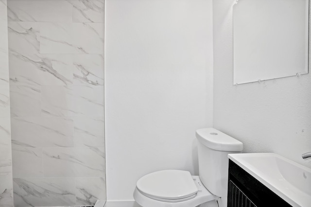 bathroom featuring tiled shower, vanity, and toilet