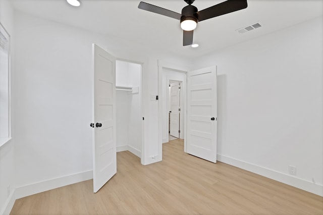 unfurnished bedroom featuring a spacious closet, ceiling fan, light wood-type flooring, and a closet